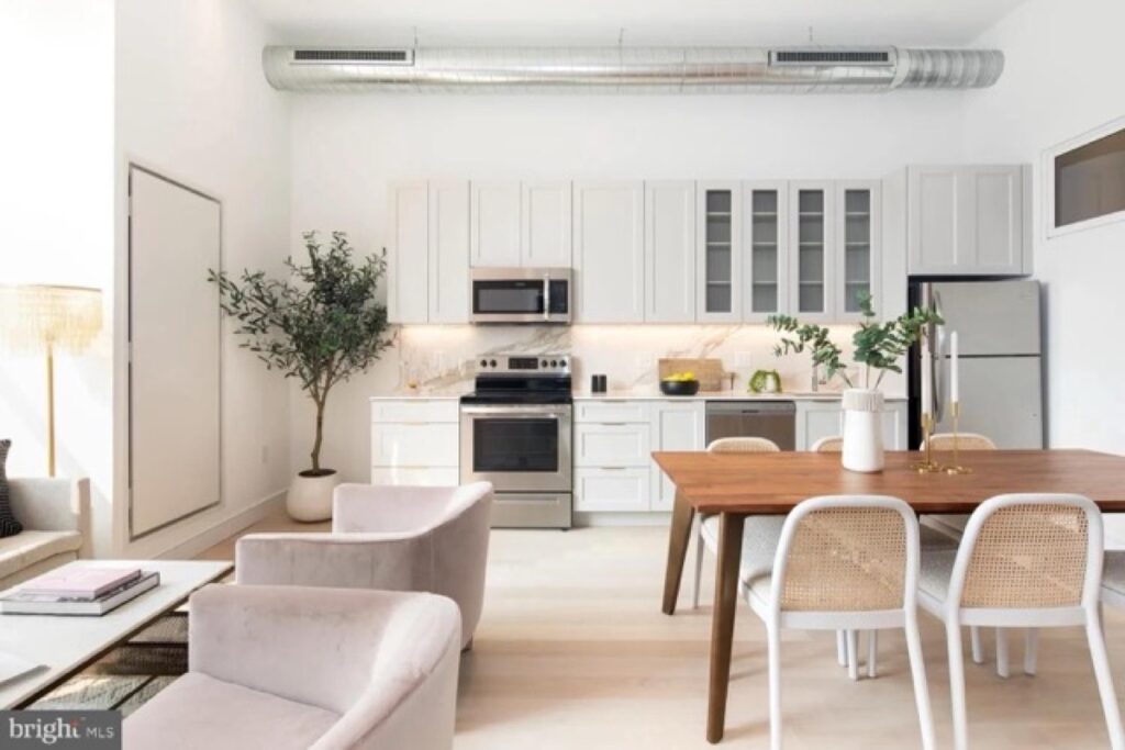 Open chef-inspired kitchen with stainless steel appliances and a wood dining table in a Poplar and Darien residence