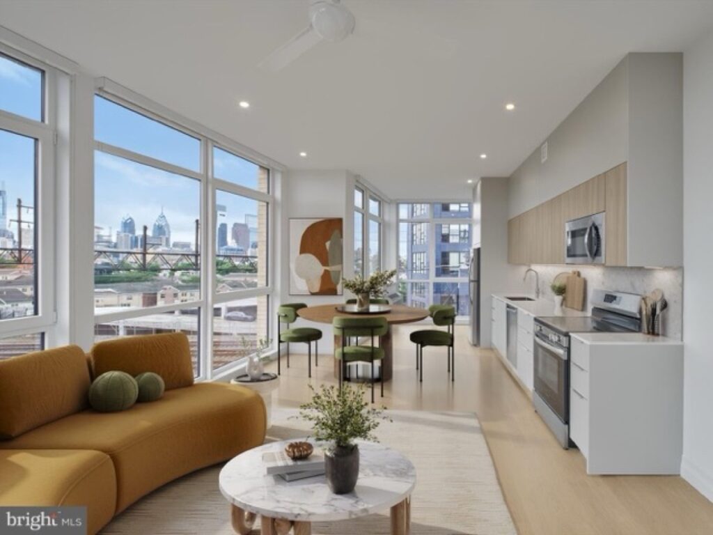 Sunlit two-bedroom living room and open kitchen with floor-to-ceiling windows framing the Philadelphia skyline at The Poplar