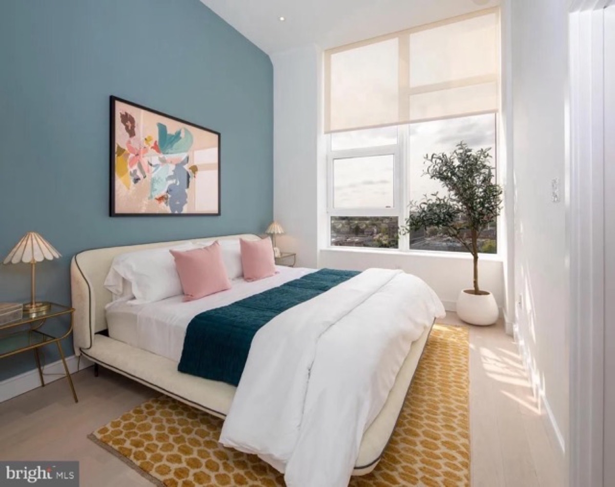 Second Bedroom at The Poplar and The Darien Second bedroom with blue accent wall, upholstered bed and large windows in a two-bedroom apartment at The Darien
